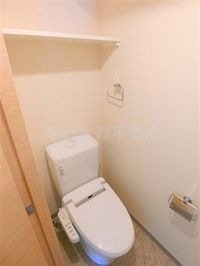 棚と温水暖房便座付きのトイレ