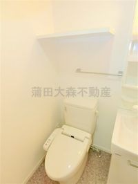 棚と温水暖房便座付きのトイレ